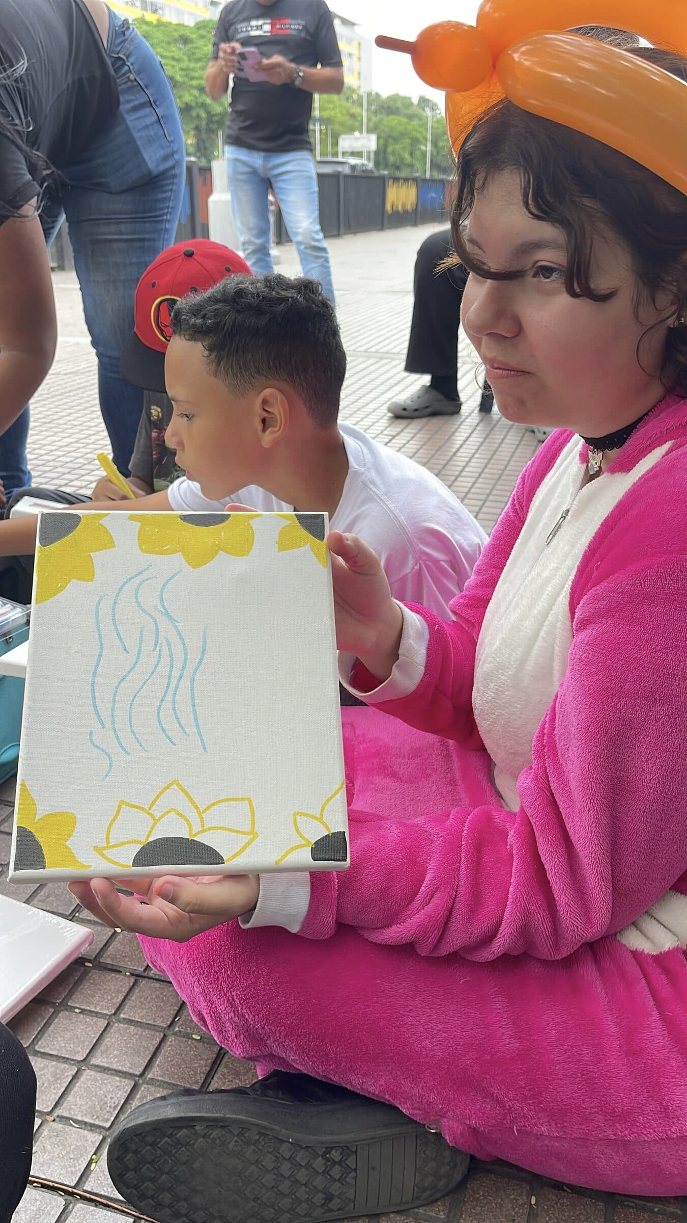 Una adolescente muestra su lienzo de girasoles pintado durante el taller de arte del campamento.