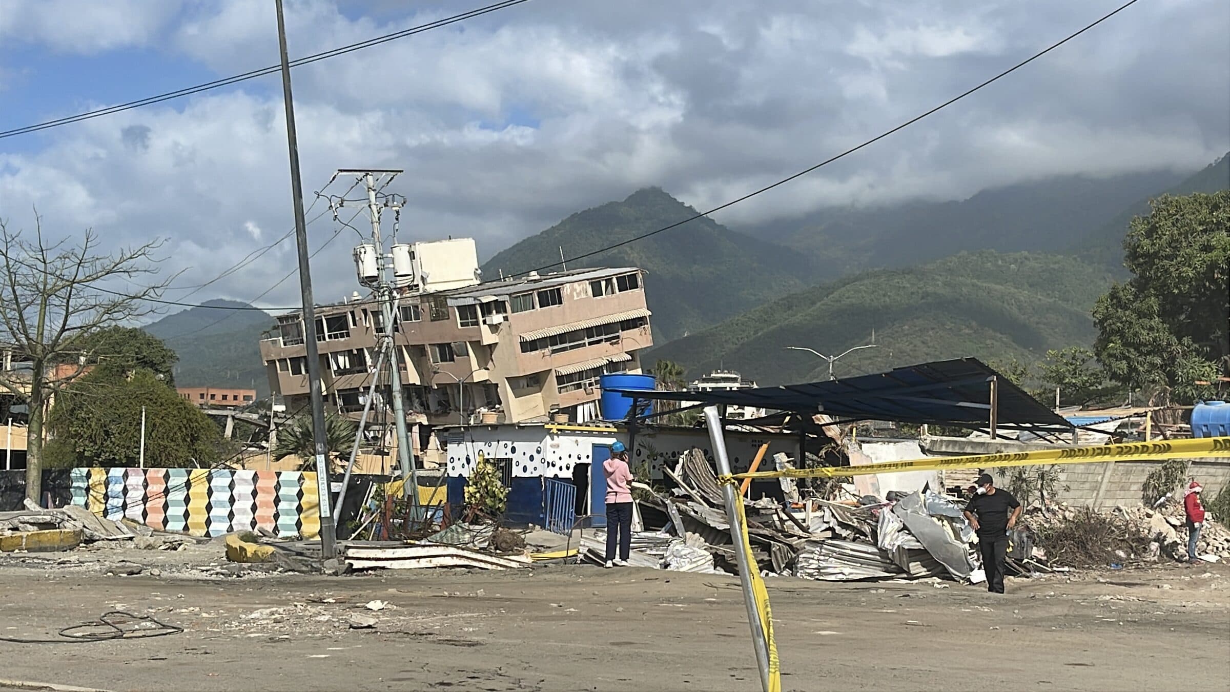Trabajadores evalúan un edificio inclinado por el terremoto detrás de un cordón de seguridad en La Guaira, Venezuela.