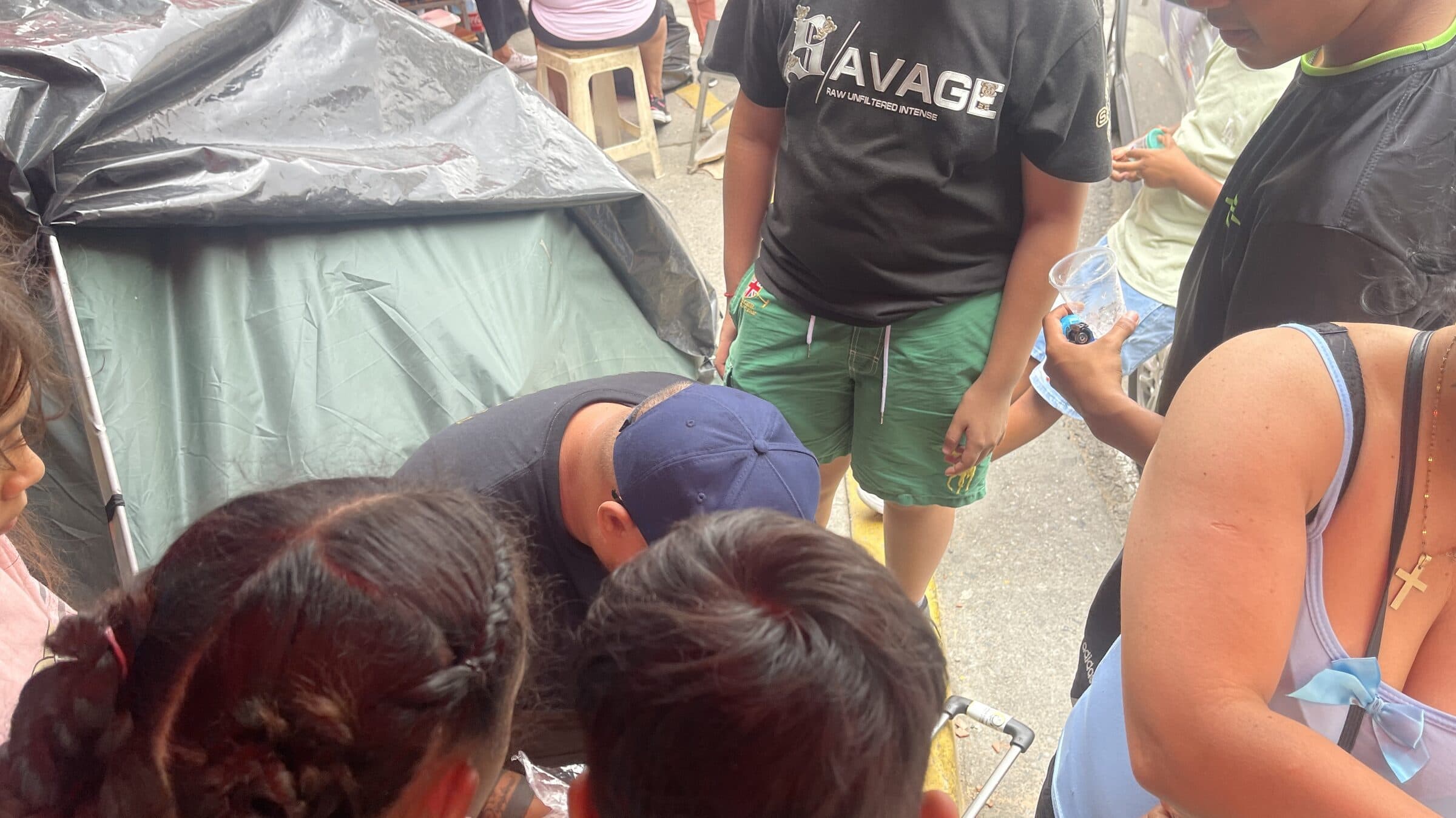 Una maleta abierta llena de insumos de higiene mientras una voluntaria de IHE los reparte a niños en el campamento.
