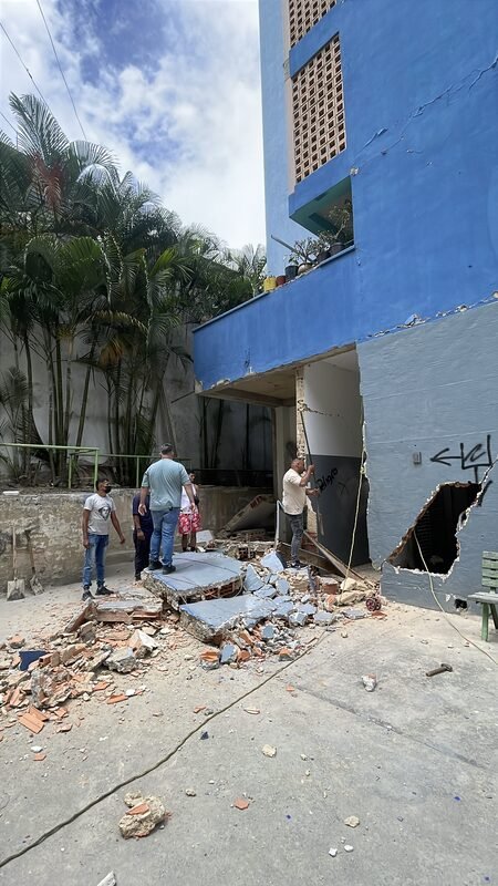 Earthquake-damaged building facade with rubble on the ground.