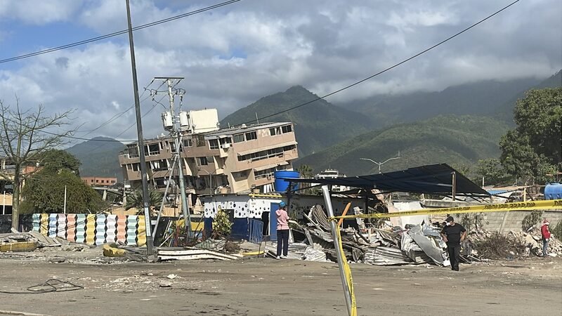 Pile of concrete rubble from a collapsed multi-story building, with mountains in the background.