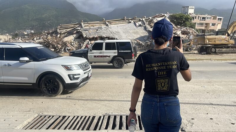 Cori, in a branded Humanitarian Response Team shirt, photographs the earthquake damage.