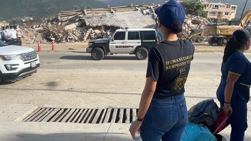 Cori, in a branded Humanitarian Response Team shirt, photographs the earthquake damage.