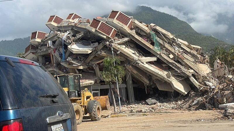 An excavator working on a pile of concrete rubble from a collapsed building.