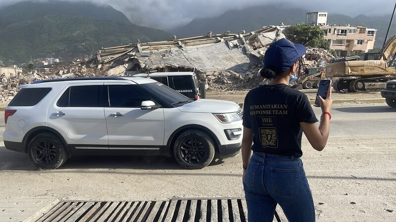 Cori, in a branded Humanitarian Response Team shirt, photographs the earthquake damage.