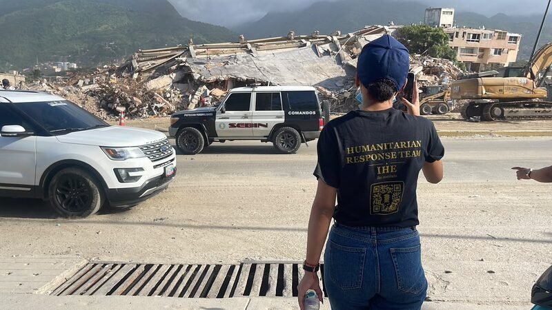 Cori, in a branded Humanitarian Response Team shirt, photographs the earthquake damage.