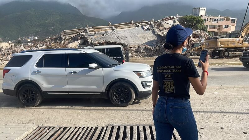 Concrete rubble and debris piled along a roadside, mountains in the background.