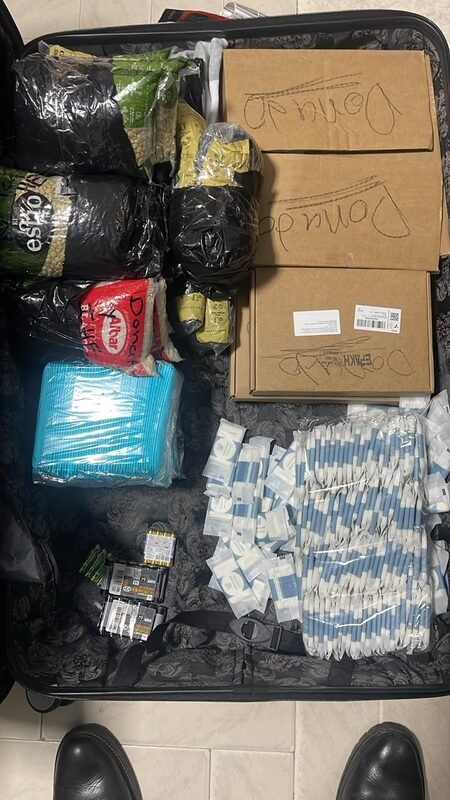 An open suitcase packed with boxed supplies and diapers.