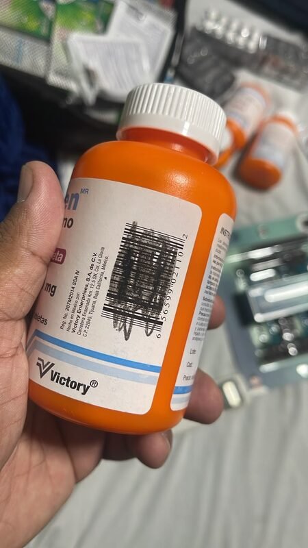 A hand holding a bottle of medication among other medical supplies.